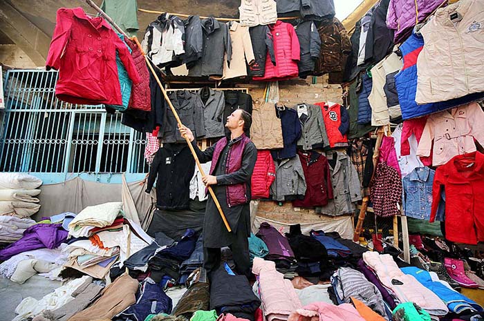 Vendor arranging and displaying old jackets and sweaters to attract the customers in the Hashtnagri area.