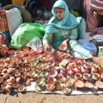 A woman vendor displaying the lams to attract the customers in connection with Dewali festival.