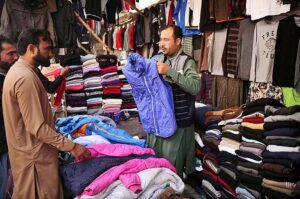 Vendor arranging and displaying old jackets and sweaters to attract the customers in the Hashtnagri area.