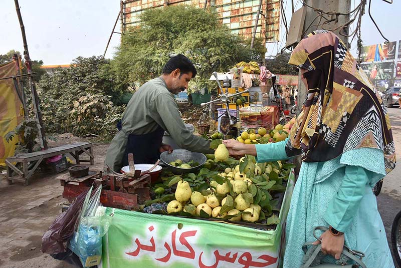 A woman buying guavas from a roadside vendor