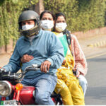 A family wearing mask while traveling on a motorcycle to avoid the smog in the provincial capital