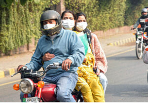 A family wearing mask while traveling on a motorcycle to avoid the smog in the provincial capital