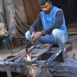 Skilled worker cutting thick iron sheet at his work place