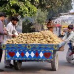 Vendor displaying and selling sweet items (Gurr) at roadside setup.