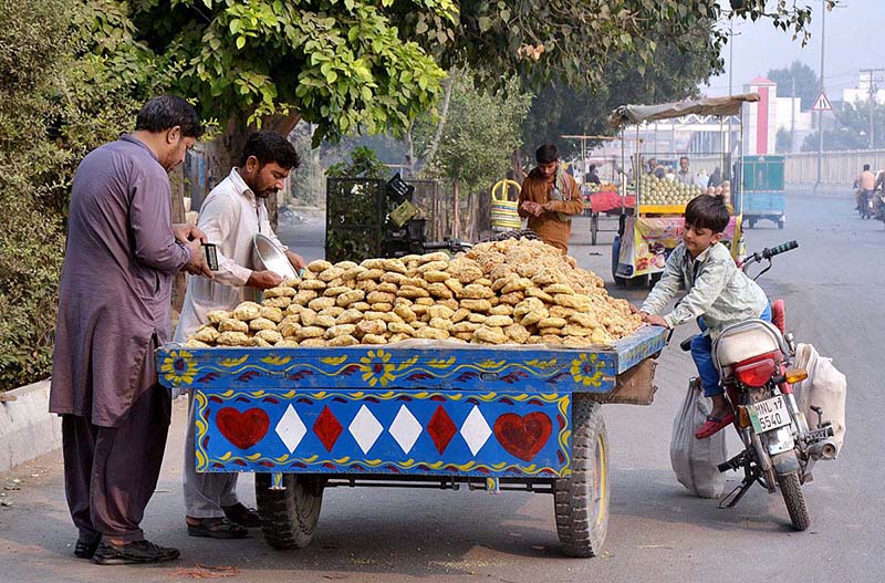 Vendor displaying and selling sweet items (Gurr) at roadside setup.