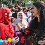 Students offering sweet to each other during function in connection with upcoming Sindhi Ajrak Topi Culture Day at Department of Criminology, University of Sindh, Elsa Kazi Campus