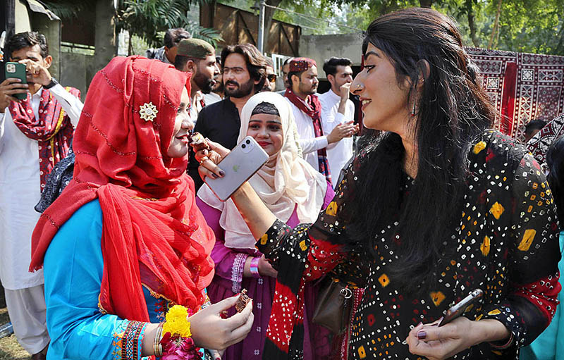 Students offering sweet to each other during function in connection with upcoming Sindhi Ajrak Topi Culture Day at Department of Criminology, University of Sindh, Elsa Kazi Campus