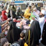 People purchasing used clothes from a roadside vendor