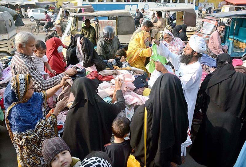 People purchasing used clothes from a roadside vendor