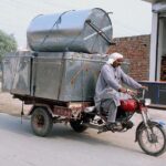 Daily wager loaded with Trunks on his motorcycle-cart on way to destination