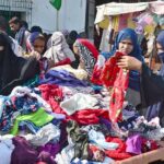 Women busy in selecting and purchasing old warm clothes from vendor at Cloth Market