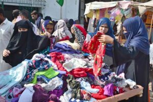 Women busy in selecting and purchasing old warm clothes from vendor at Cloth Market