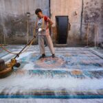 A worker washing Afghani carpet after knitting at his workplace near Haji Camp