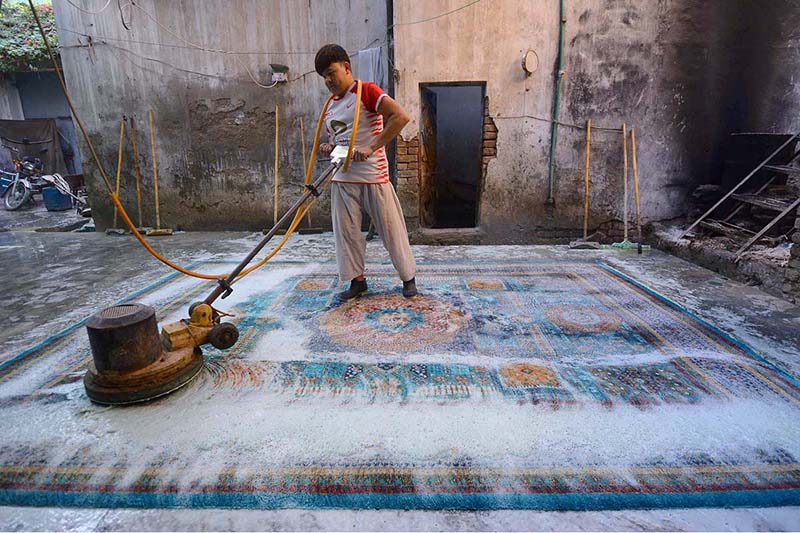 A worker washing Afghani carpet after knitting at his workplace near Haji Camp