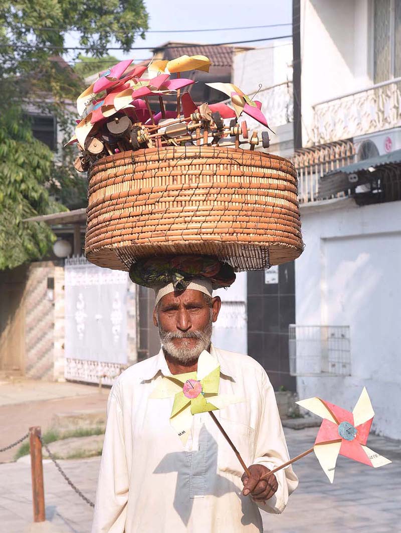An elderly man is selling handmade paper flowers to earn livelihood for children at Shah Jamal An elderly man is selling handmade paper flowers to earn livelihood for children at Shah Jamal