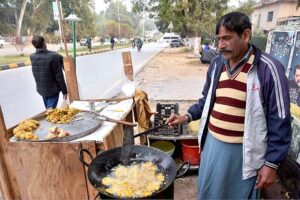 A vendor frying and displaying fritters at G-7