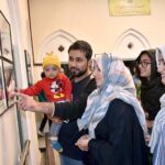 A family is observing the portrait of Dr. Allama Muhammad Iqbal at Iqbal Manzil.