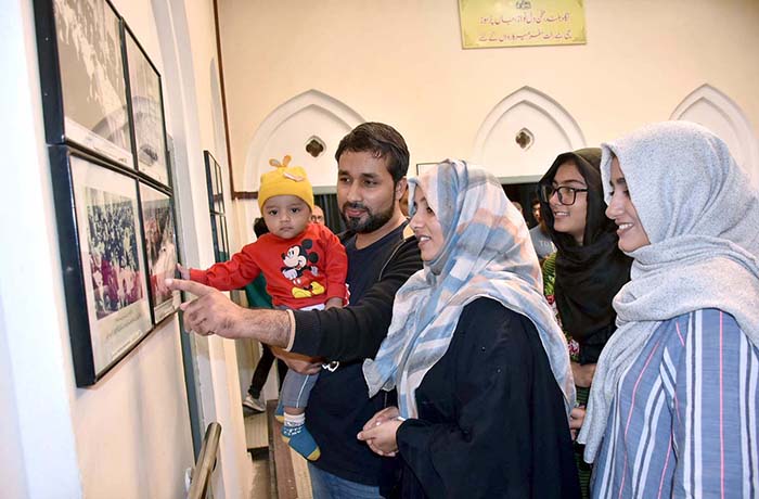 A family is observing the portrait of Dr. Allama Muhammad Iqbal at Iqbal Manzil.