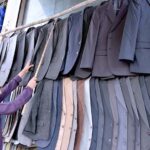 Vendor arranging and displaying Displaying coats at his road side setup