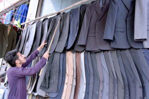 Vendor arranging and displaying Displaying coats at his road side setup