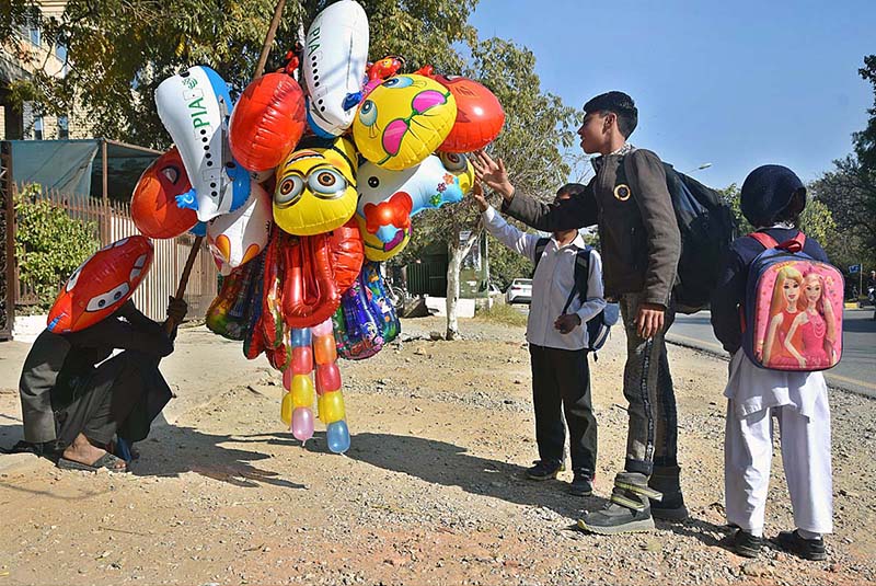 School children keenly viewing different shapes balloons displayed by vendor at G-7 in Federal Capital