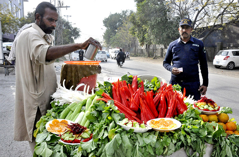 A street vendor sprinkle water to the radish and carrot to keep them fresh on his bicycle setup in federal capital