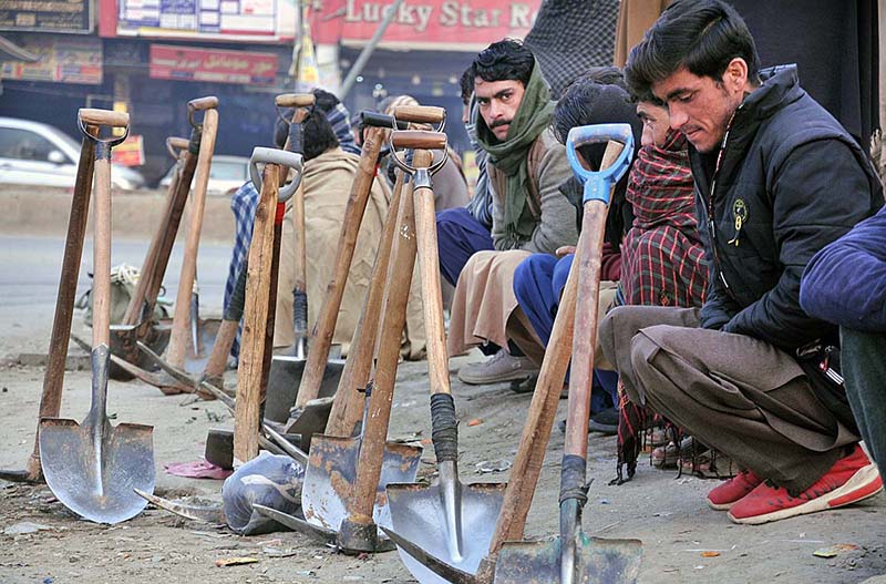 Labourers alongwith their tools sitting on roadside waiting for clients to be hired for work during morning time at Khanna Pul