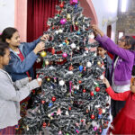 Girls decorating Christmas tree at St. Xavier Catholic Church in connection with Christmas celebration.