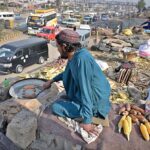 A vendor busy in roasting corn cobs at his roadside setup at Pirwadhai area