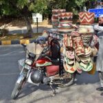 A street vendor displaying traditional household items on his motorcycle to attract the customers at F-7 sector in Federal Capital.