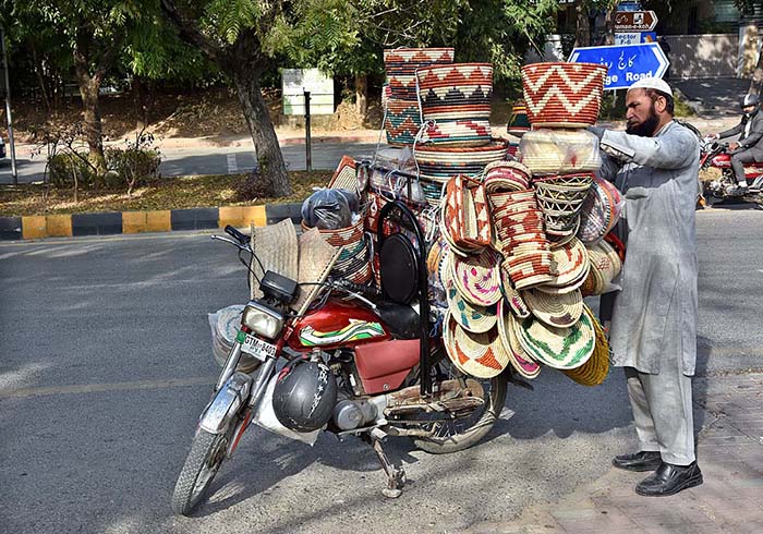 A street vendor displaying traditional household items on his motorcycle to attract the customers at F-7 sector in Federal Capital.