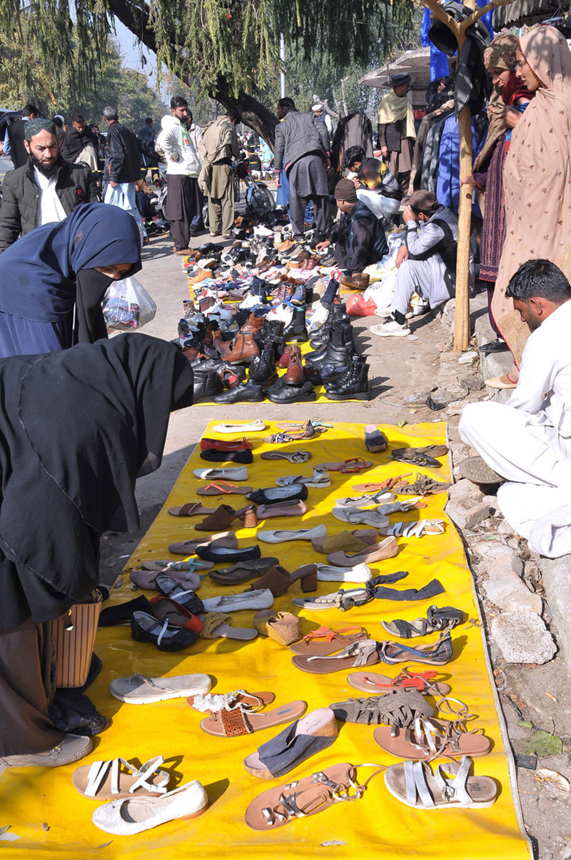 People purchasing second hand shoes at vendors’ roadside setup near Aabpara market