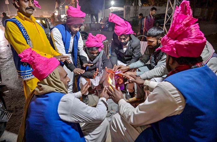 Traditional drummers sitting around fire to keep themselves warm due to cold weather at Faizabad.