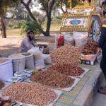 A vendor is displaying and selling dry fruit at his roadside setup.