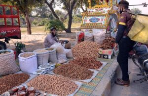 A vendor is displaying and selling dry fruit at his roadside setup.