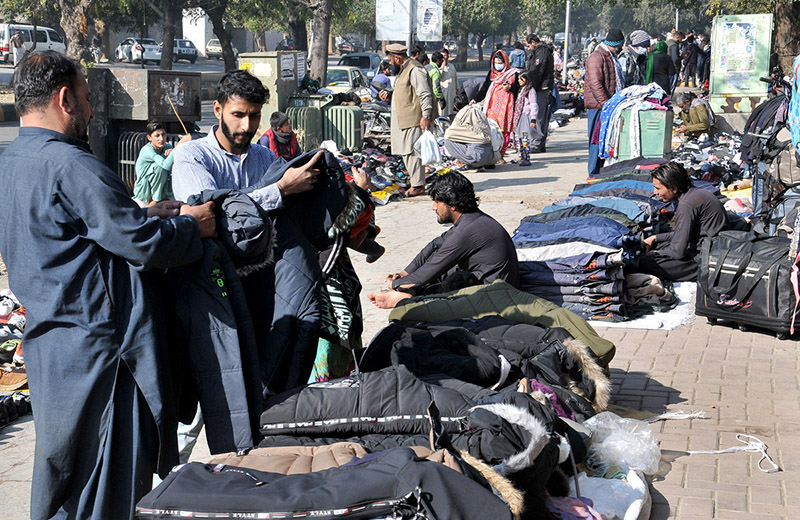 People purchasing second hand shoes at vendors’ roadside setup near Aabpara market