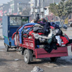 Customer selecting and purchasing second hand warm clothes from the vendor at Lehtrar Road.