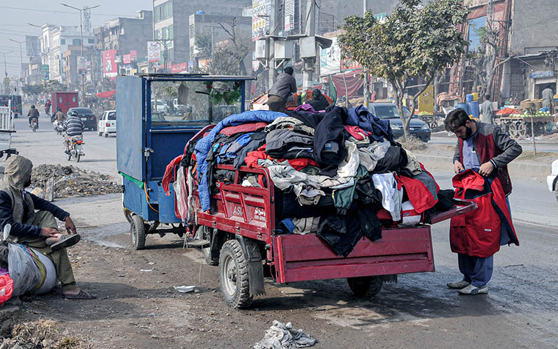 Customer selecting and purchasing second hand warm clothes from the vendor at Lehtrar Road.