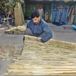A worker preparing traditional bamboo chick blinds at his workplace on the roadside.