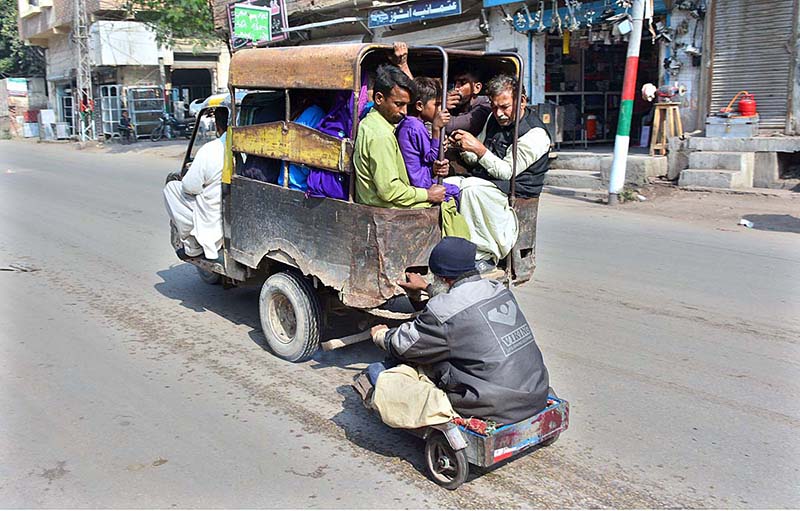 A disable person on cart holding tri-cycle while travelling on road to reach his destination