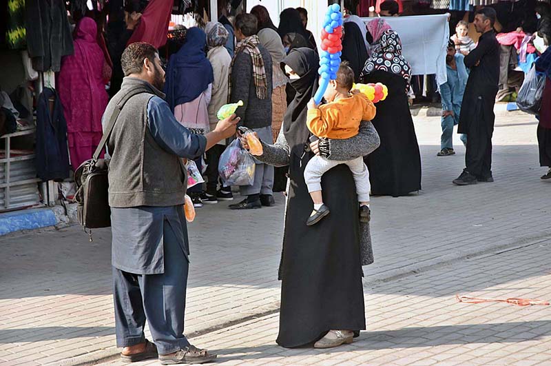 Woman selecting and purchasing warm clothes at Weekly Bazaar Peshawar Mor