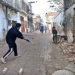A group of youngsters playing cricket in the street