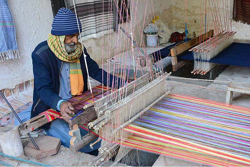 An elderly worker busy in making shawl at his work place