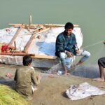 Fisherman busy in preparing the net for catching fishes at water canal.