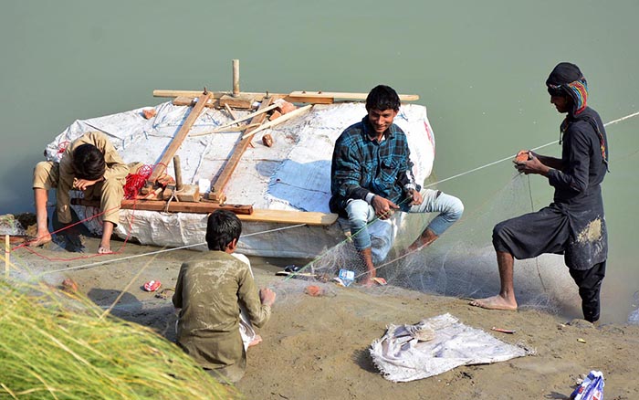 Fisherman busy in preparing the net for catching fishes at water canal.