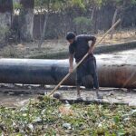 A worker of Irrigation Department cleaning heap of garbage from Rakh Branch Canal.