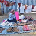 An elderly vendor displaying the Sindhi cultural dresses to attract the customers at roadside
