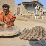 An elderly worker busy in preparing clay-made lamp at his workplace.