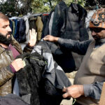 A customer is buying a winter outer jacket from road side vendor.