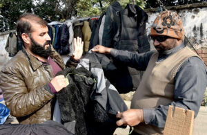 A customer is buying a winter outer jacket from road side vendor.
